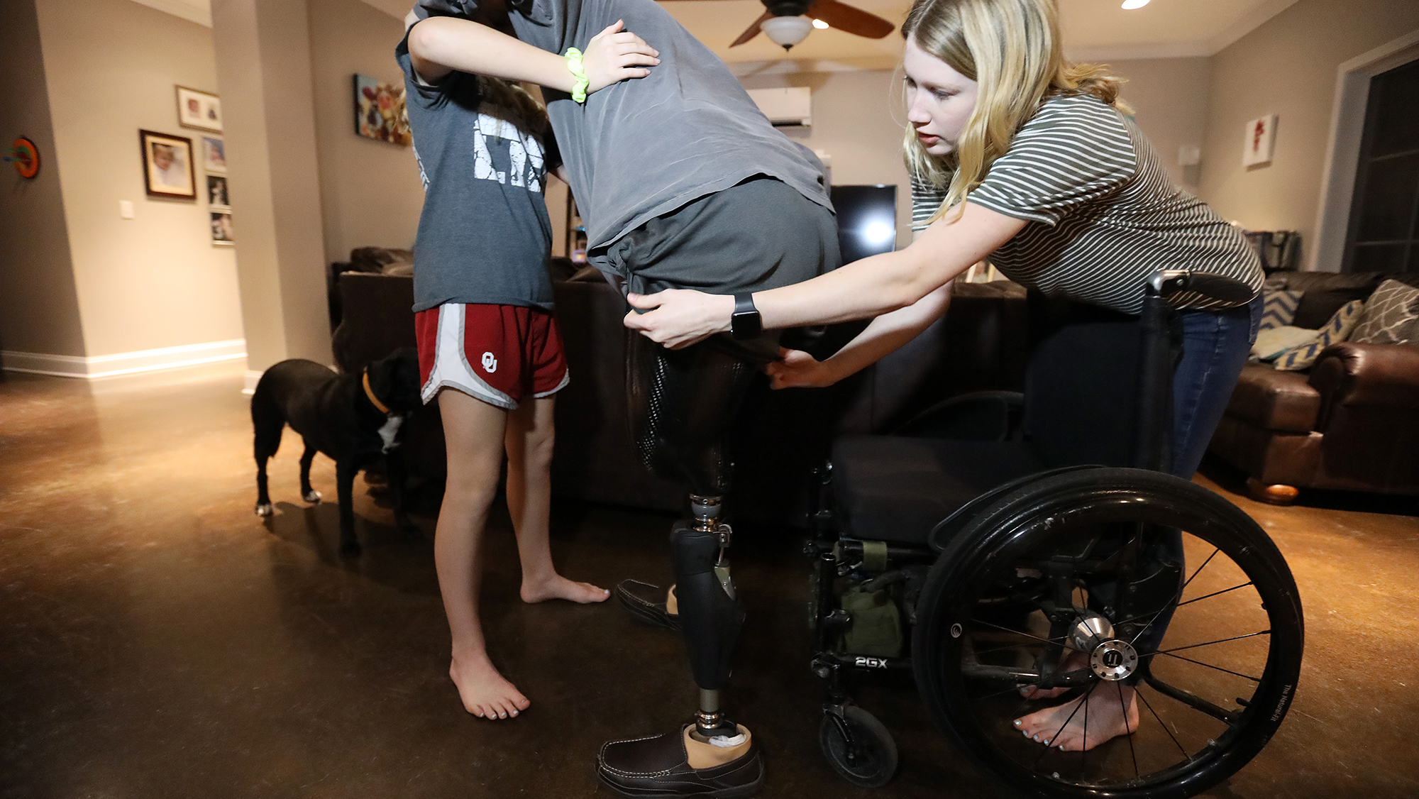 Deryn Allen and younger sister Ryann help their father, Chaz, a double amputee out of his wheelchair in McMinnville, TN. VINO WONG/SKY BLOSSOM FILMS